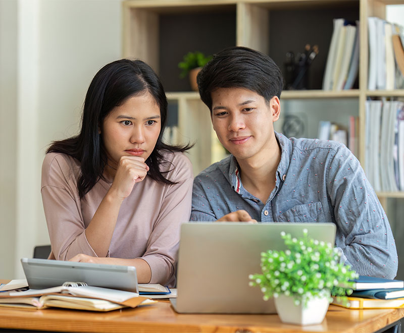 Man and woman reading information on laptop in their preferred language